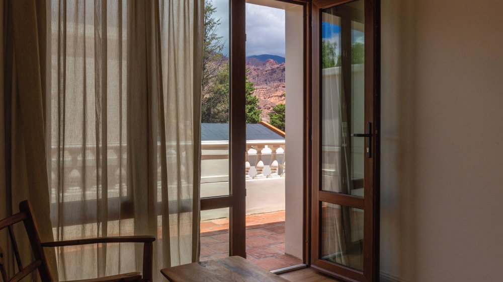 Balcón con vista a los cerros de las habitaciones estándar en planta alta con aire acondicionado del Hotel El Candil en Tilcara, Jujuy.