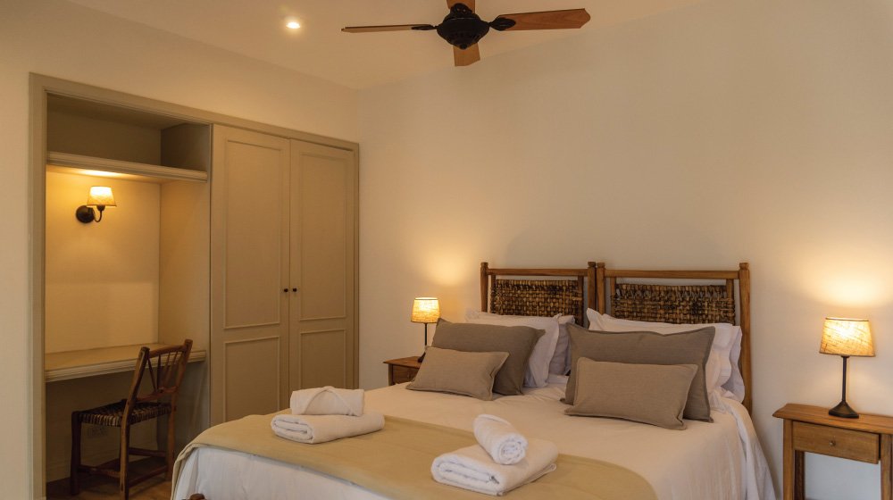 Cama doble y vista a los cerros de las habitaciones estándar en planta baja sin aire acondicionado del Hotel El Candil en Tilcara, Jujuy.